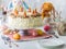 A whole carrot cake on a cake stand with cream cheese frosting surrounded by Easter decorations.