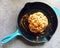 Whole cauliflower head to be roasted in blue cast-iron pan