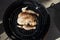 Whole chicken covered with spices sits in the center of a barrel smoker ready to cook