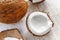 Whole coconut and chopped into chunks and chips on a light white wooden background. Top view