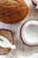 Whole coconut and chopped into chunks and chips on a light white wooden background. Top view