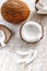 Whole coconut and chopped into chunks and chips on a light white wooden background. Top view