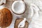 Whole coconut and chopped into chunks and chips on a light white wooden background. Top view