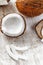 Whole coconut and chopped into chunks and chips on a light white wooden background. Top view