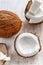 Whole coconut and chopped into chunks and chips on a light white wooden background. Top view