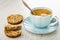 Whole cookie with different seeds, broken cookie, spoon in cup with coffee on saucer on table
