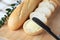 Whole and cut baguettes with fresh butter on wooden board, closeup