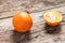 Whole and Cut in Half Orange lying on Weathered Wooden Table