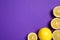 Whole and cut lemons on purple background, flat lay. Space for text