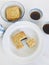 A whole and cut moon cake in a round dish, served with tea, on white marble background. Vertical.