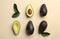 Whole and cut ripe avocadoes with green leaves on beige background  flat lay