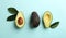 Whole and cut ripe avocadoes with green leaves on light blue background, flat lay