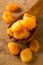 Whole dried apricots fruit in wooden spoon on wooden board