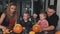 Whole family carves pumpkins for halloween on table at home