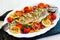 Whole fish trout with vegetables and dill on a white plate and dark wooden background