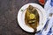 A whole flounder, baked in the oven, on a light plate on a brown concrete background