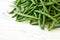 Whole French green string beans on white rustic wood. Space for