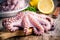 Whole fresh raw octopus on cutting board with lemon