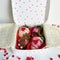 Whole fresh strawberries covered in white and brown chocolate decorated with heart sprinkles in a white box decorated with hearts,