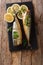 Whole freshly smoked mackerel served with lemons and parsley closeup on a slate board on the table. Vertical top view