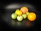 Whole fruits green apples, orange, grapefruit and lemon on black background. Concept - vegetarian and healthy food to improve the