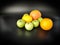 Whole fruits green apples, orange, grapefruit and lemon on black background. Concept - vegetarian and healthy food to improve the