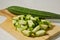 A whole gambas or luffa gourd and pieces of luffa gourd fruit on a wooden cutting board