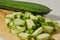 A whole gambas or luffa gourd and pieces of luffa gourd fruit on a wooden cutting board