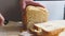 Whole grain bread put on kitchen wood plate with a chef holding knife for cut. Cutting fresh crusty bread close-up. The