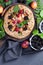 Whole-grain galette with plums and berries on dark background, t