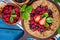 Whole-grain galette with plums and berries on dark background, t