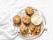 Whole grain muffins with dried apricots, oatmeal, apple, carrots and nuts on rustic cutting board on light background, top view. H