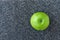 Whole Granny Smith apple on a plastic man made faux gray granite cutting board