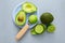 Whole and half avocado on a saucer, with a spoonful of pulp and fresh halves of green lime