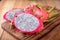 Whole and half cut fresh dragon fruit on wooden board
