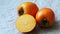 Whole and half of fresh ripe persimmons, kaki fruit. Japanese persimmon Diospyros kaki