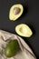 Whole and halved avocados on black table