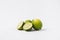 whole and halved limes laying on white background