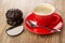 Whole and halves of chocolate marshmallow, coffee in red cup, spoon on saucer on table