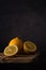 Whole and halves of a fresh ripe lemon lie in a group on an old plank table against a dark soft background. side view. moody