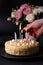 Whole holiday cake with crumbly shortcrust pastry and mini meringue. Man lights candles on a cake. Birthday cake with lit candles