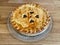 Whole homemade baked to a crisp apple pie, side view, decorated with hearth symbols.