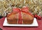 Whole loaf cake wrapped in a red and gold ribbon.