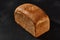 Whole loaf of fresh, palatable baked white bread against black background with copy space. Close-up