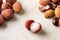 Whole lychee, shells and bones near half peeled lychee fruit Litchi chinensis on a white kithen table. Fruits and vegetables,