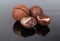 Whole macadamia nuts and empty nutshell on dark surface