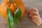 Whole mandarins with leaves and three slices on wooden ledge