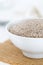 Whole, organic white chia seeds heap in white bowl with bright kitchen background