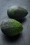 Whole pair of green avocado, on black background