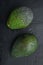 Whole pair of green avocado, on black background, top view or flat lay